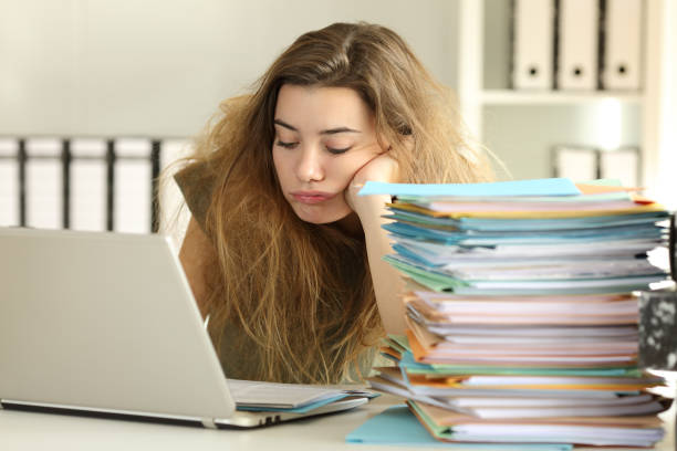 Exhausted intern with tousled hair working at office stock photo