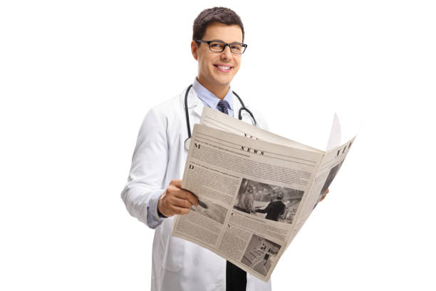 istock Doctor with a newspaper looking at the camera and smiling 905970194