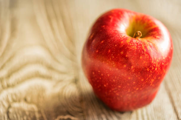 istock Red juice ripe apple on wooden background 905979418
