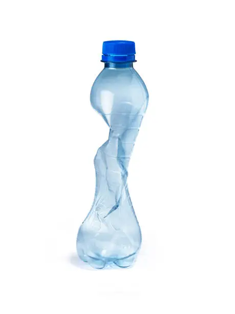 shot of a single plastic water bottle, crushed and crumpled ready for the trash and landfill, highlighting the environmental impact of plastics   usage