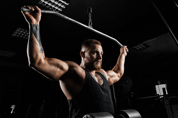 istock Professional athlete performs an exercise in the gym. Pulls the bar to the back of the head. 905989904