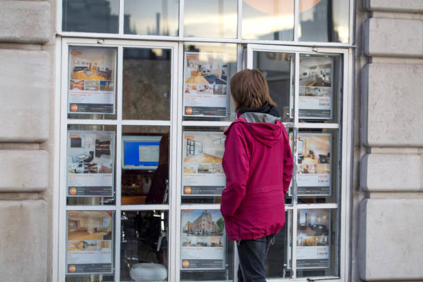 Woman looking at houses and flats in the window of an estate agent in London, UK stock photo