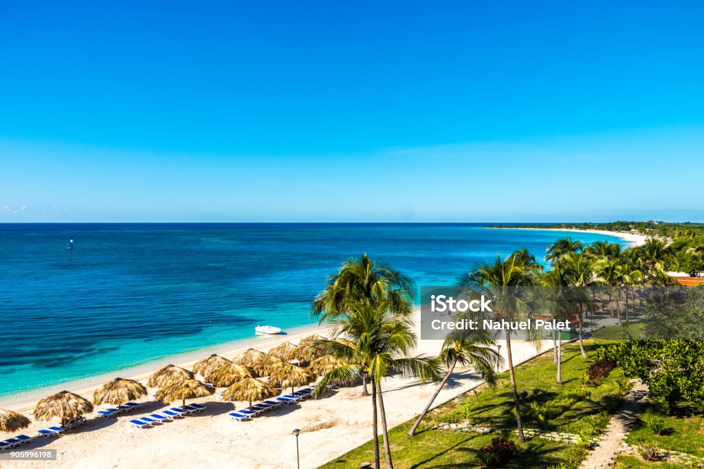 Amazing view of a paradisiac beach in Playa Ancon Amazing view of a paradisiac beach in Playa Ancon, palm trees, translucent blue water, straw umbrellas, sun. Blue Stock Photo