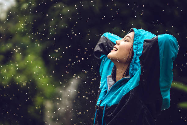 屋外でレインコートを着たアジア人女性。彼女�は幸せです。 - umbrella women storm yellow ストックフォトと画像