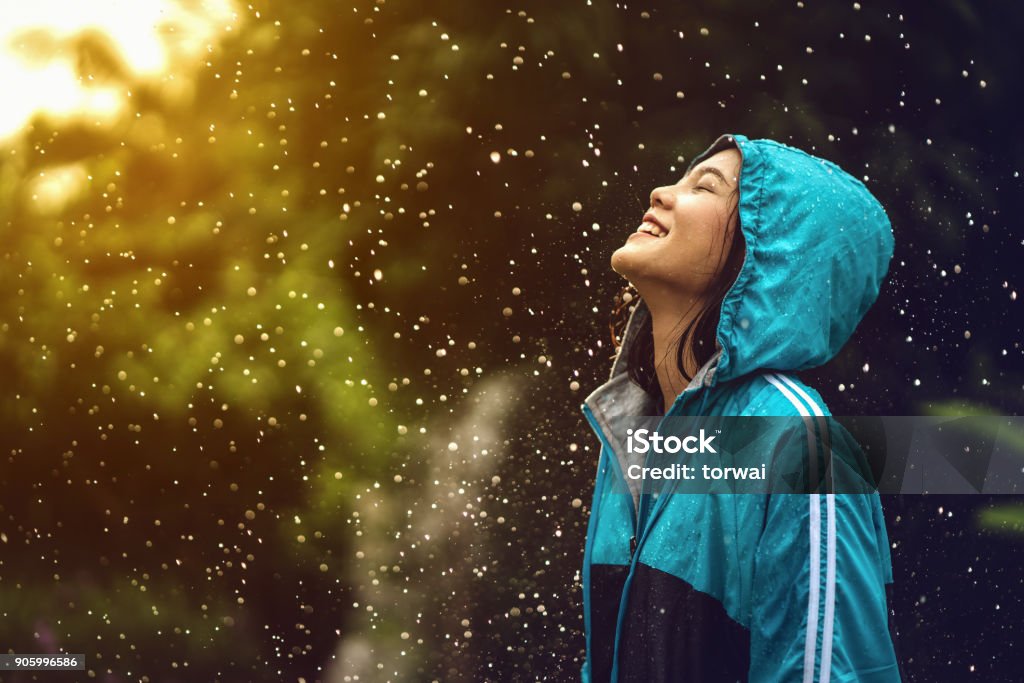 Asian woman wearing a raincoat outdoors. She is happy. Rain Stock Photo
