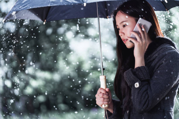 アジアの女性は、パラソルを使用している、雨が降っています。彼女が呼んでいます。 - wet dress rain clothing ストックフォトと画像