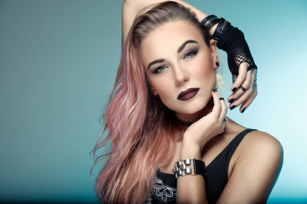 Beautiful woman with stylish pink hair Portrait of a beautiful woman with stylish pink hair over blue background, attractive young girl with dark lips, special style makeup for Gothic party rocker nails stock pictures, royalty-free photos & images
