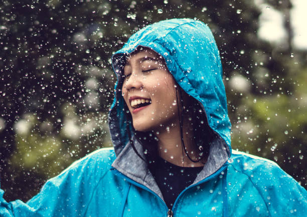 azjatka ubrana w płaszcz przeciwdeszczowy na świeżym powietrzu. jest szczęśliwa. - umbrella women storm yellow zdjęcia i obrazy z banku zdjęć