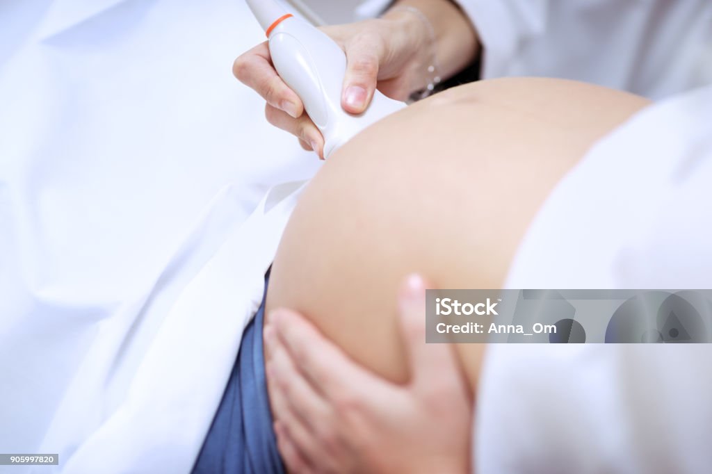 Doctor making ultrasound scanning for pregnant woman Doctor making ultrasound scanning for pregnant woman, ultrasound is safe and painless, closeup photo of a women's abdomen on third trimester, body part, conceptual photo of healthy pregnancy Ultrasound Stock Photo