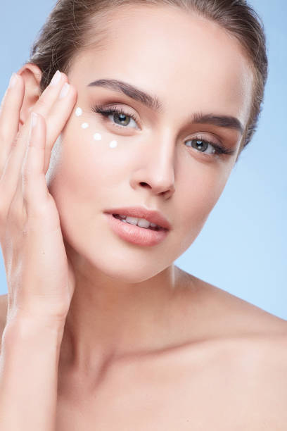 istock Young woman applying cream under eyes 906001012