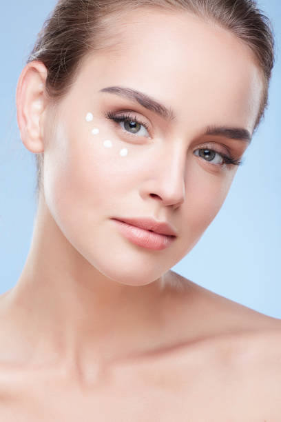 Young woman applying cream under eyes stock photo