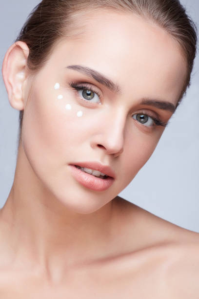 istock Young beautiful woman with cream under eyes 906001186
