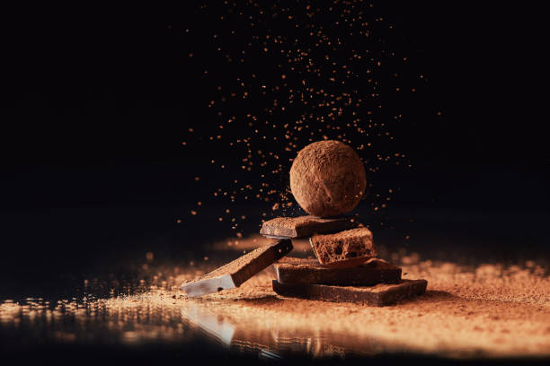 close up view of tasty truffles on black close up view of truffle on chocolate bars with cocoa powder on black food styling stock pictures, royalty-free photos & images