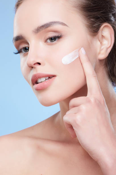 istock Young woman applying cream on face 906001992