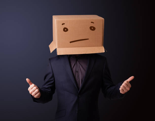 istock Young man gesturing with a cardboard box on his head with straight face 906008304