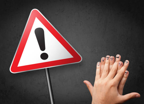 istock Happy smiley fingers looking at triangle warning sign with exclamation mark 906022190