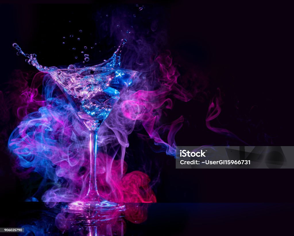 cocktail splashing in a smoky background cocktail splashing and multicolored smoke in a black background Cocktail Stock Photo