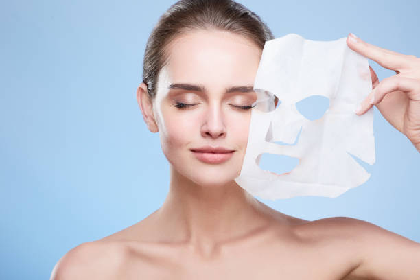 Woman removing mask from face stock photo