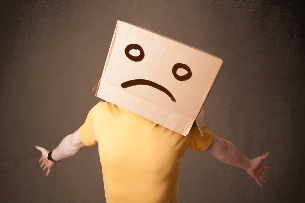 istock Young man with a brown cardboard box on his head with sad face 906029756