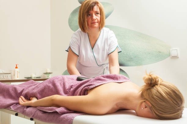istock Female masseuse doing massage with hot stones 906030166