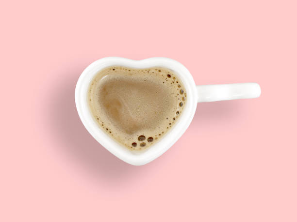 milk coffee in white heart shape ceramic coffee cup on pastel pink background romantic kitchenware and hot drink for Valentine's Day, flat lay close-up top view froth decoration stock pictures, royalty-free photos & images