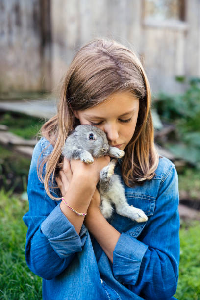istock Cute girl cuddling a baby rabbit on her head outdoors in spring. 906036710