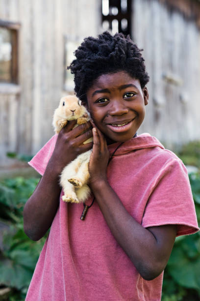 istock Cute african-american boy holding a baby rabbit outdoors in spring. 906037132