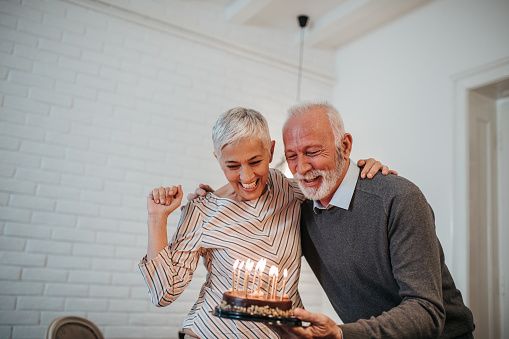 Mature couple celebrating holding a birthday cake