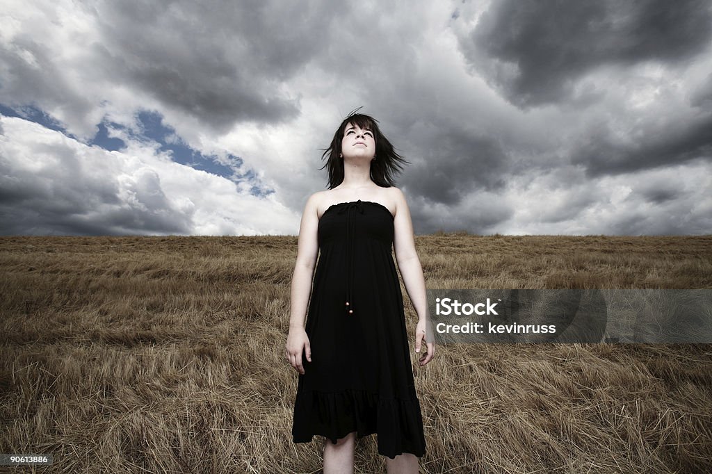 Jovem mulher em um campo de vento com nuvens de tempestade - Foto de stock de Adolescente royalty-free