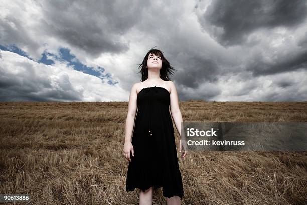 Foto de Jovem Mulher Em Um Campo De Vento Com Nuvens De Tempestade e mais fotos de stock de Adolescente