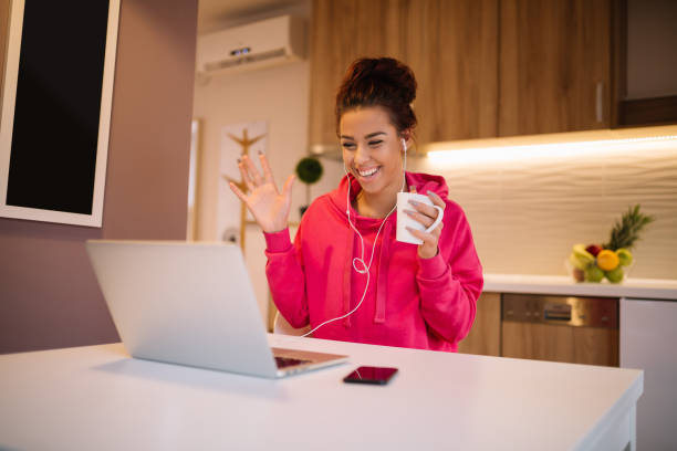 Young beautiful girl video chatting. Girl with smile on her face waving to the camera on her laptop. stock photo