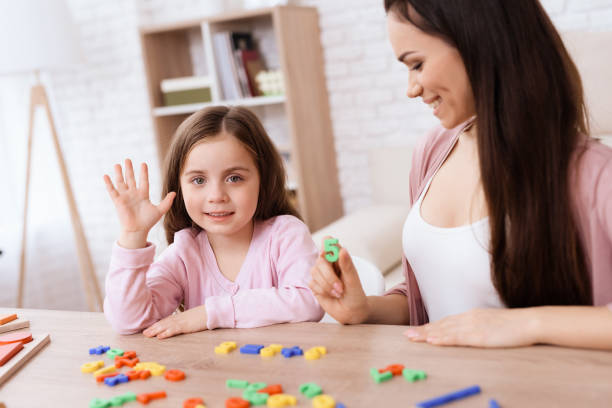 istock A young woman is teaching a little girl a math. 906147064