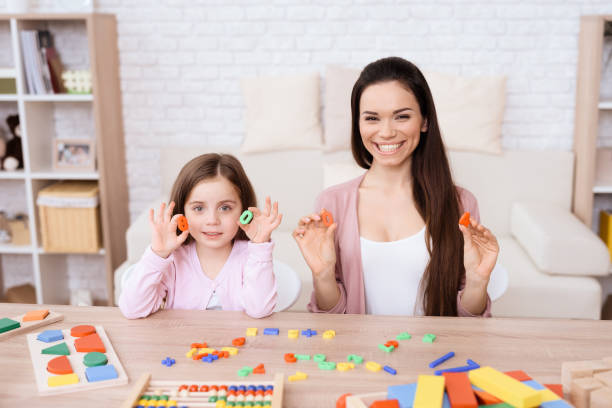 istock A young woman is teaching a little girl a math. 906147070
