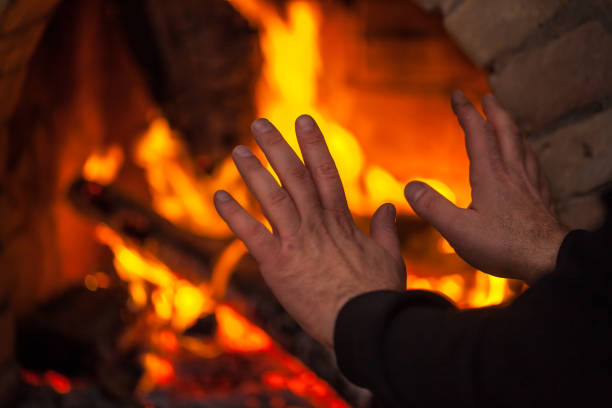 istock A fire burns in a fireplace, hands in the direction of the fireplace 906151920