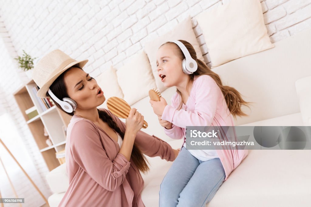 Mom and daughter sing songs at home. Mom and daughter sing songs at home. They use combs like microphones. They play together. Mother Stock Photo