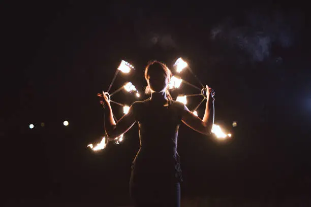 Young and strong woman creating a performance with a hand fans, lit on fire.