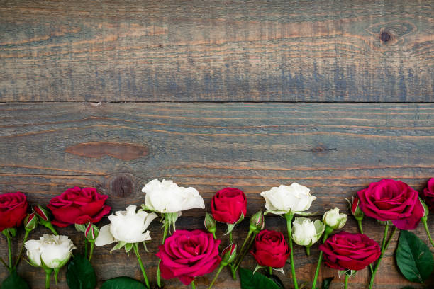 istock Floral pattern made white and red roses on wood background. Flat lay, top view. Floral background 906196912