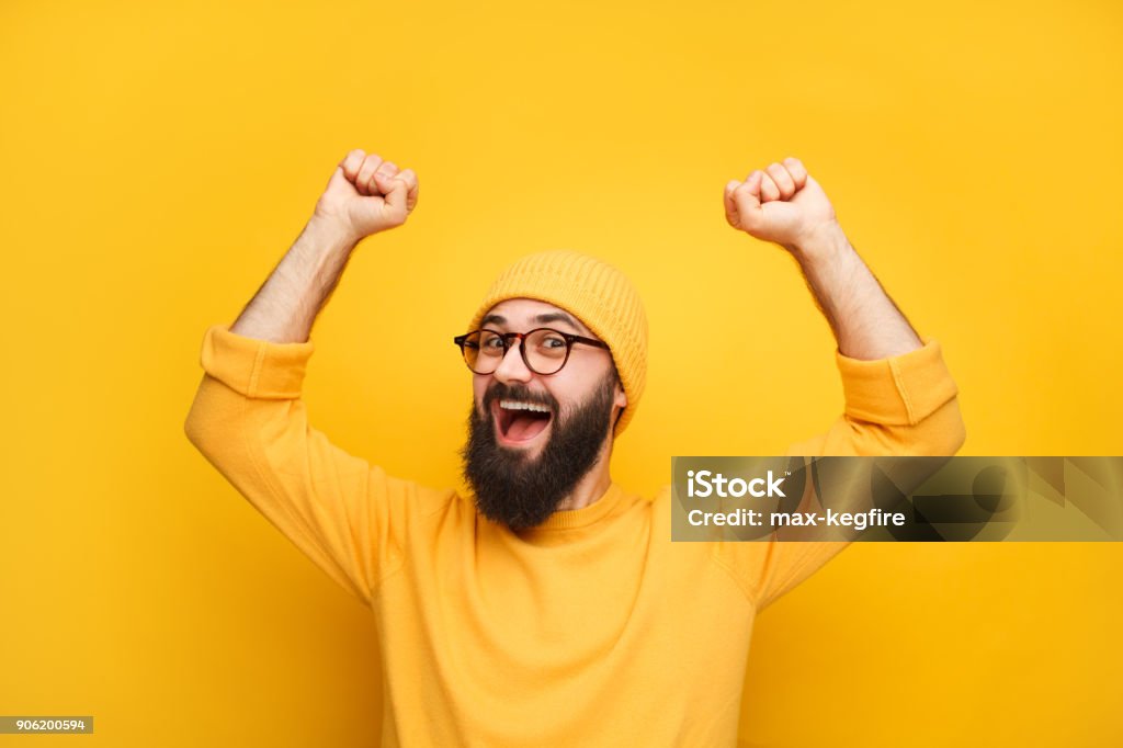 Man in yellow clothes feeling happy Cheerful bearded man in yellow clothes feeling happy and posing with hands up. Men Stock Photo