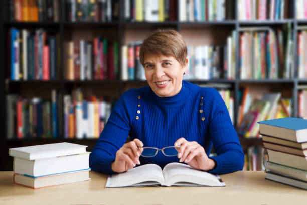 istock Happy senior woman  with books in library. 906248282