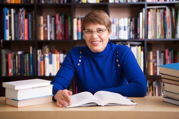 istock Happy senior woman  with books in library. 906248290