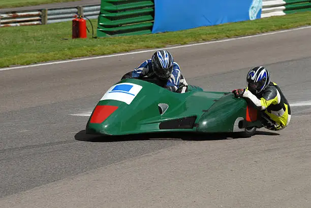 A green 600 cc motorbike and sidecar accelerating away from a corner