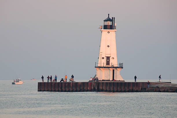 Fishing Pier, Fisherman and Lighthouse stock photo