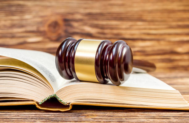 istock Judge's wooden hammer with open book on the table. Close up. Justice concept. 906320242