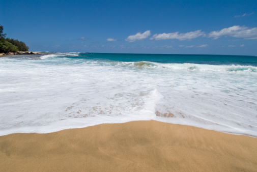 beautiful deserted beach in Kauai,yellow sands,white foamy waves and blue skies