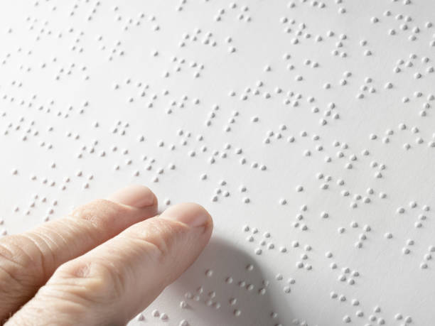 Hand of a blind person reading some braille text touching the relief. Empty copy space for Editor