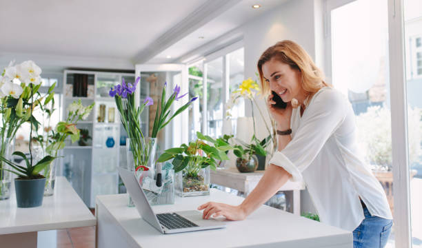 florist taking order on mobile phone - garden center flower women plant imagens e fotografias de stock