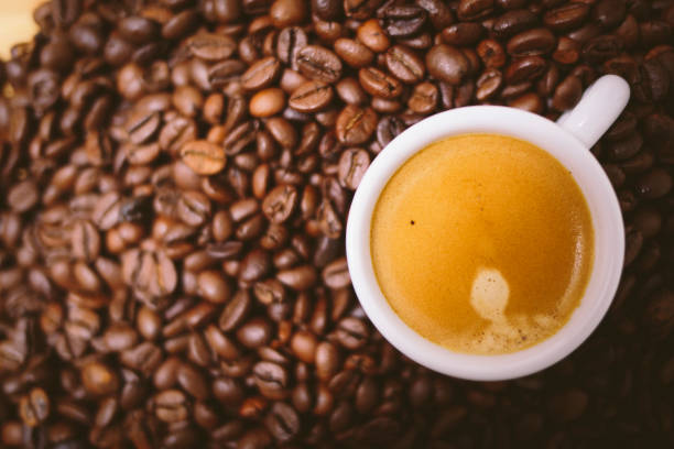istock Espresso coffee with cream on a white cup on a brown coffee beans background 906359940