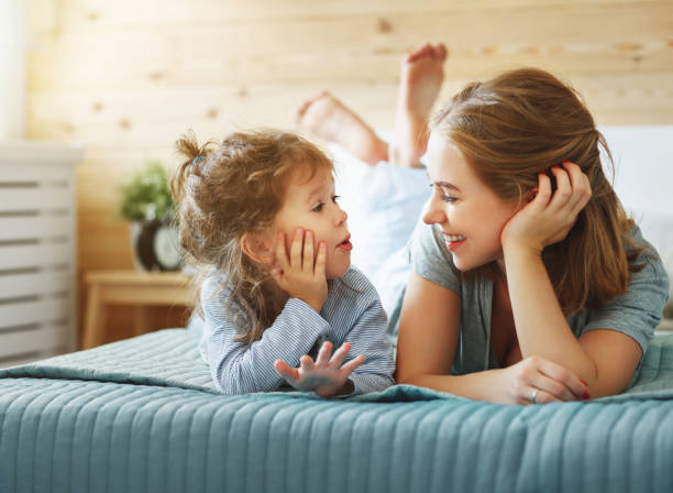 幸せ家族母と子の娘をベッドで笑う - 赤ちゃん　会話 ストックフォトと画像