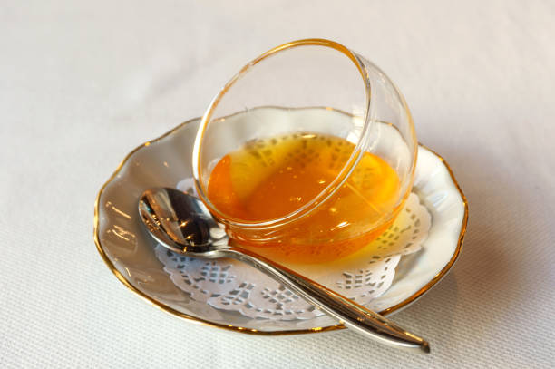istock honey in a glass vase on white plate with a teaspoon 906393464