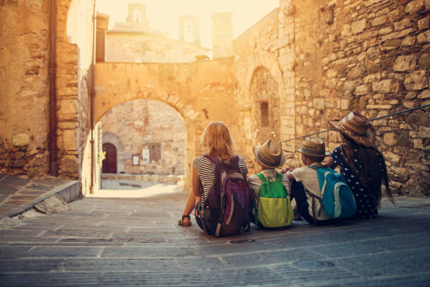 Tourists family enjoying peaceful street of small italian town Mother and kids tourists sightseeing beautiful Italian town of Campiglia Marittima. Sunny summer day. Italy, Tuscany.

 kids travelling  culture stock pictures, royalty-free photos & images